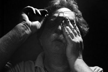 yorgun orta yaşlı adam gözlerini ovuyor.