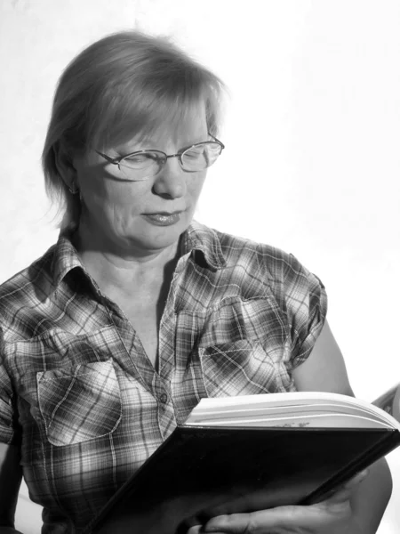 Black and white portrait of middle aged woman in eyeglasses with book — Stock Photo, Image