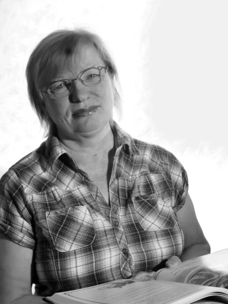 Чорно-білий портрет жінки середнього віку в окулярах з книгою — стокове фото