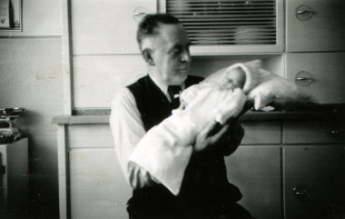 yelek, beyaz gömlek ve kravat bir bebek bezi içinde tutan adam