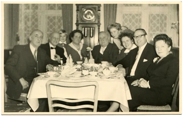 群的男人和女人穿着晚礼服坐在餐桌旁 — 图库照片