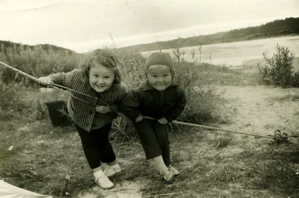 Liten flicka och pojke poserar lutar på fjäderben tält vid ån — Stockfoto