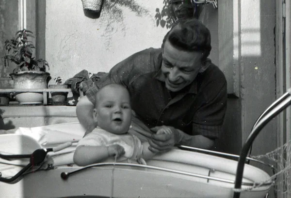 Hombre de mediana edad sosteniendo la mano de un niño sentado en un transporte para bebés —  Fotos de Stock