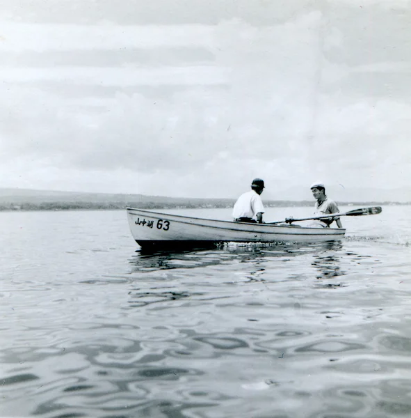 Two young men floating on the lake in a boat — Stock Photo, Image