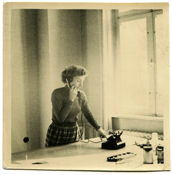 Woman standing in front of the desk and talking on the phone — Stock Photo, Image