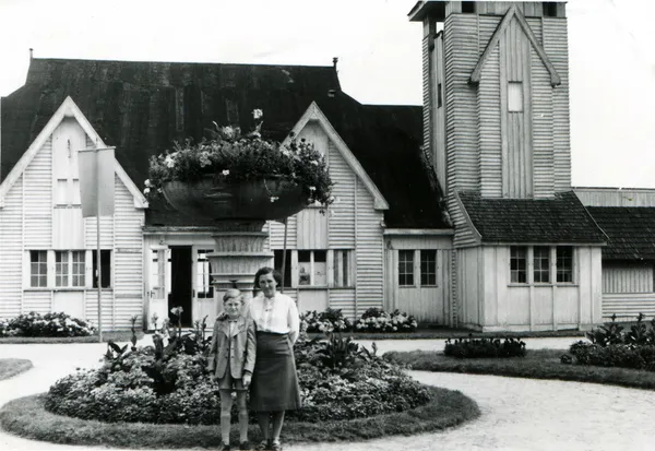 Vrouw met jongen op de achtergrond van flowerbed en huis — Stockfoto