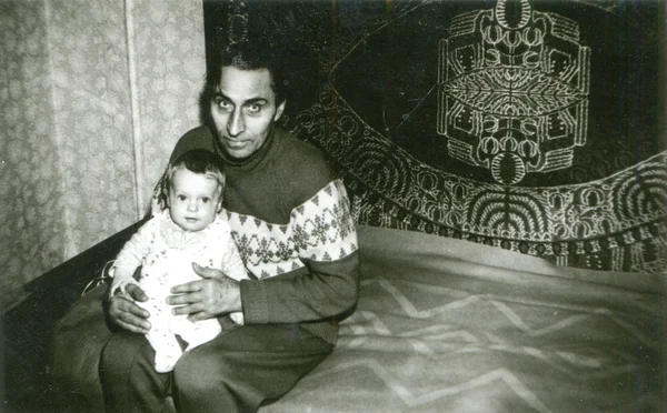 Yatağı üzerinde oturan ve küçük bir kızı tutan adamı — Stok fotoğraf