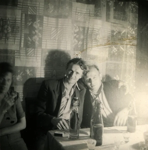 Deux jeunes hommes et une femme assis à une table — Photo