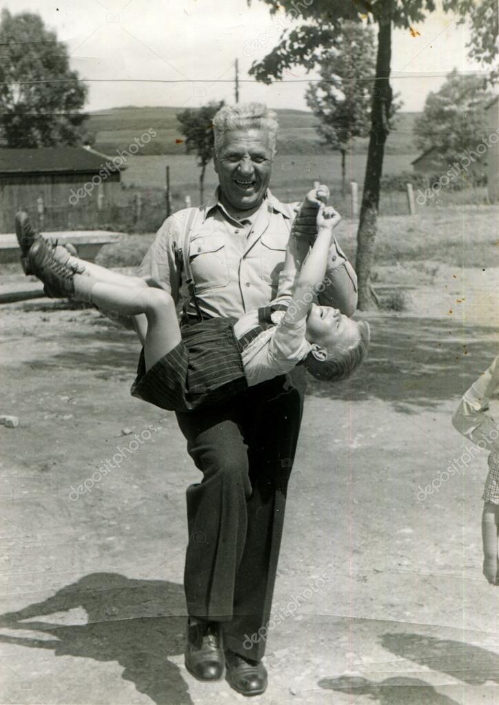 GERMANY - 1960s: An antique photo shows joyful grandfather carries a grandson