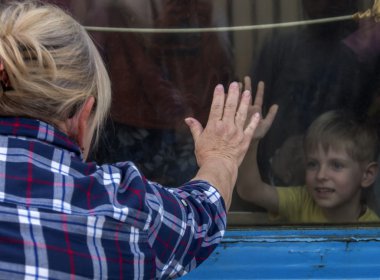 People with their children look through the window of a train leaving for Kiev clipart