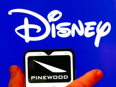 Kiev, Ukrayna - 29 Ocak 2022: Bu resimde Pinewood Stüdyoları logosu arka planda Disney logosu olan bir akıllı telefon ekranında gösteriliyor..