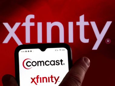 Almanya - 25 Mart 2022: Bu resimde, Comcast Cable (Xfinity) logosu arka planda Xfinity logosu bulunan bir akıllı telefon ekranında gösteriliyor