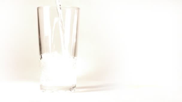 Mineraal water wordt gegoten in een glas op witte achtergrond — Stockvideo