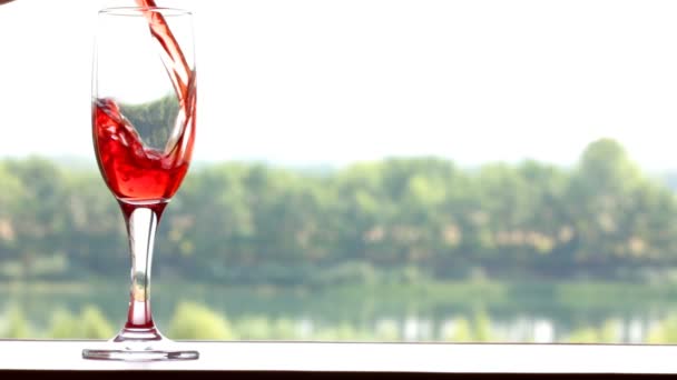 Glas gefüllt mit Rotwein auf sommerlichem Hintergrund — Stockvideo