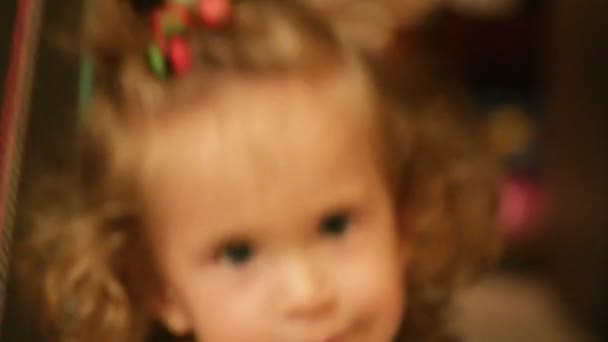 Щаслива маленька дівчинка сидить на гойдалках — стокове відео