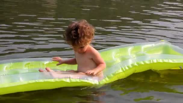Baby bathing in river on inflatable mattress — Stock Video