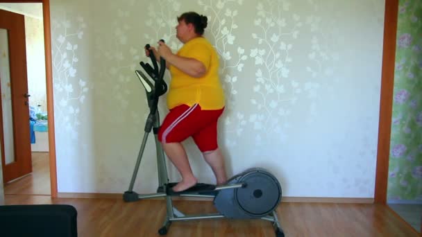 Женщина с избыточным весом тренируется на тренерском эллипсоиде — стоковое видео