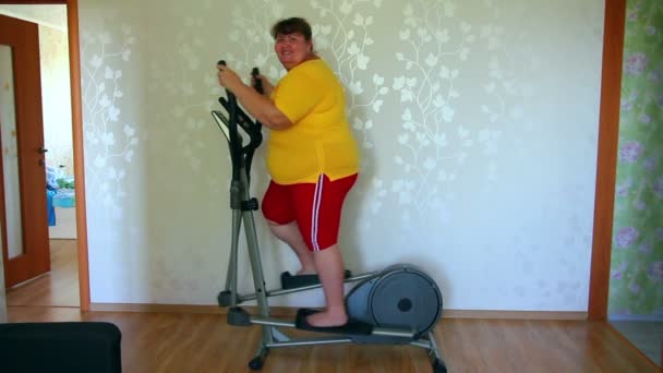 Overweight woman exercising on trainer ellipsoid — Stock Video
