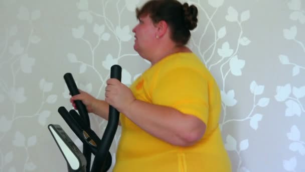 Antrenör elipsoid üzerinde egzersiz yapan kilolu bir kadın. — Stok video