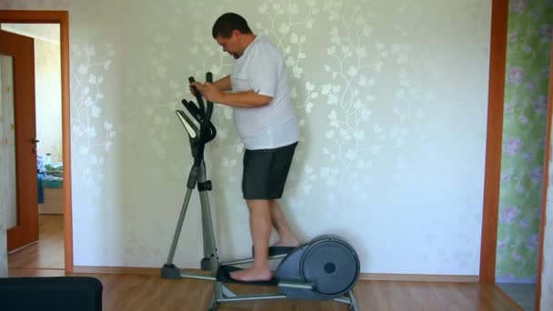 Overweight man exercising on trainer ellipsoid — Stock Video