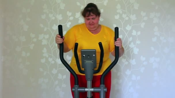 Overweight woman exercising on trainer ellipsoid — Stock Video