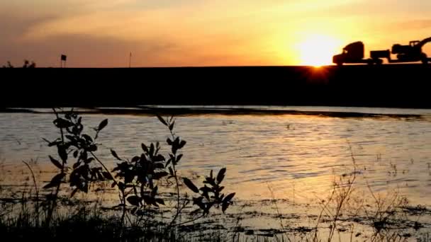 Jezero a auta siluety na silnici proti západu slunce — Stock video