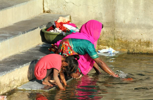 Индийская женщина с дочерью стирает одежду в озере — стоковое фото