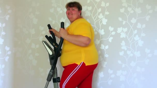 Overweight woman exercising on trainer ellipsoid — Stock Video