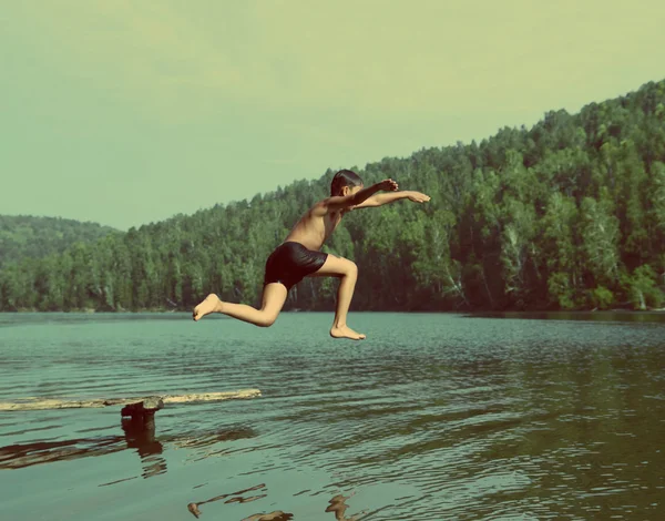 boy jumping in lake - vintage retro style