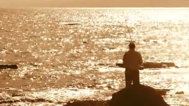 Fisherman with spinning silhouette at sea sunset — Stock Video