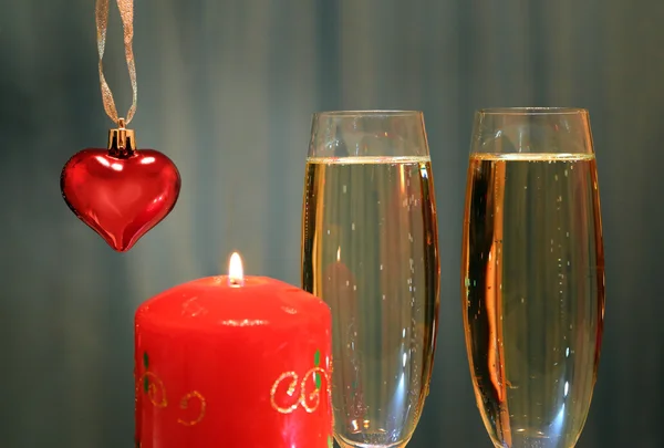 Glasses with champagne with heart and candle — Stock Photo, Image