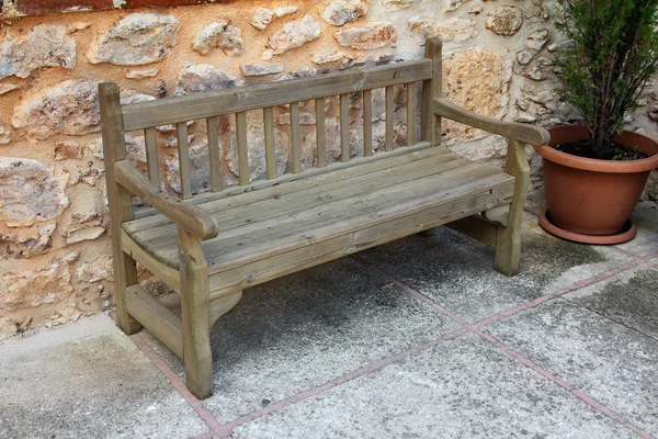 Old wooden bench near stone wall — Stock Photo, Image