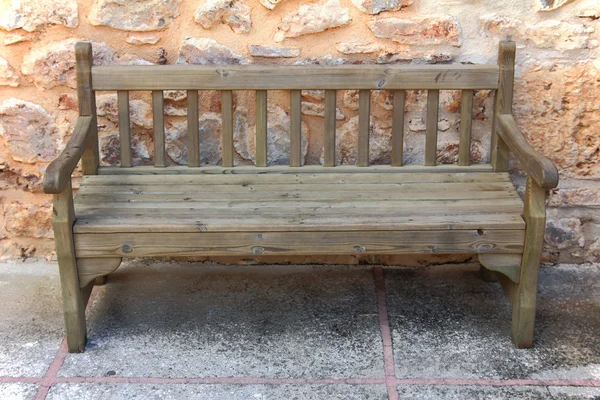 Old wooden bench near stone wall — Stock Photo, Image