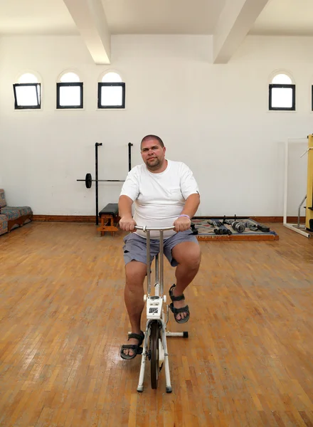 Hombre con sobrepeso en simulador de bicicleta —  Fotos de Stock