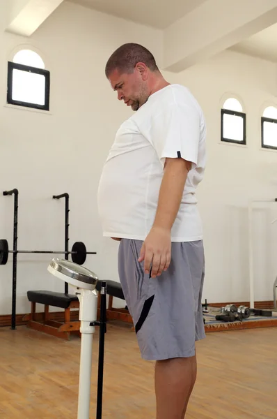 Мужчина с избыточным весом на весах в тренажерном зале — стоковое фото