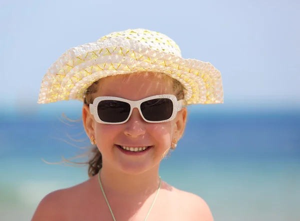 Счастливая девочка в солнцезащитных очках на пляже — стоковое фото