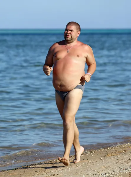 Übergewichtiger Mann läuft am Strand — Stockfoto