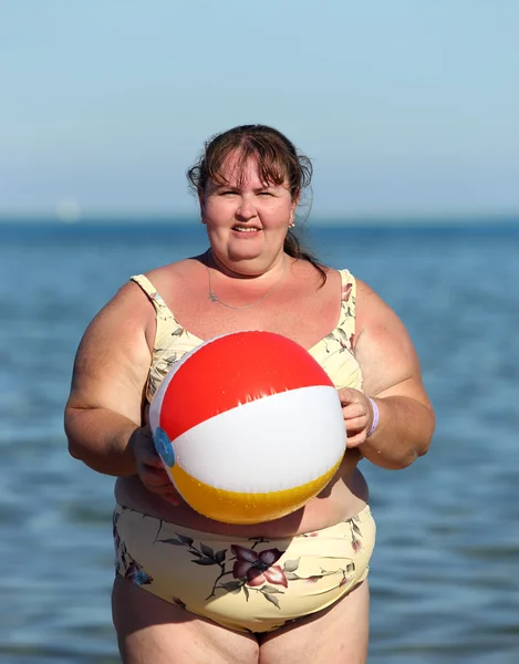 Overweight woman with ball on beach — Stock Photo, Image