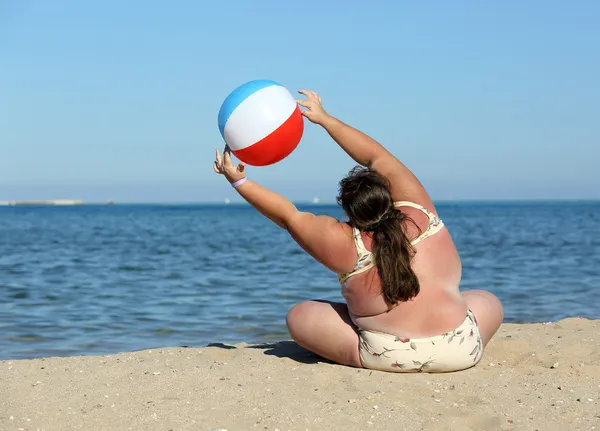 Overweight woman doing gymnastics on beach — Stock Photo, Image