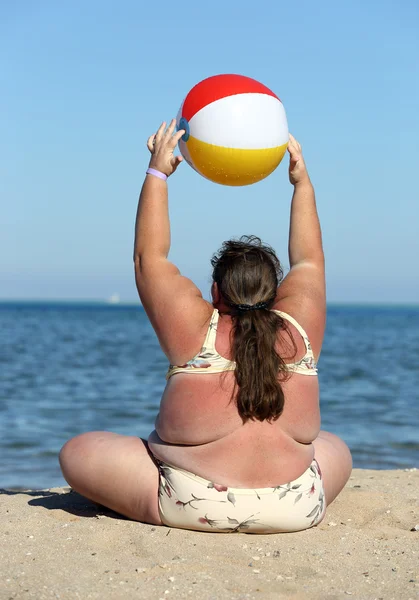 Overweight woman doing gymnastics on beach — Stock Photo, Image