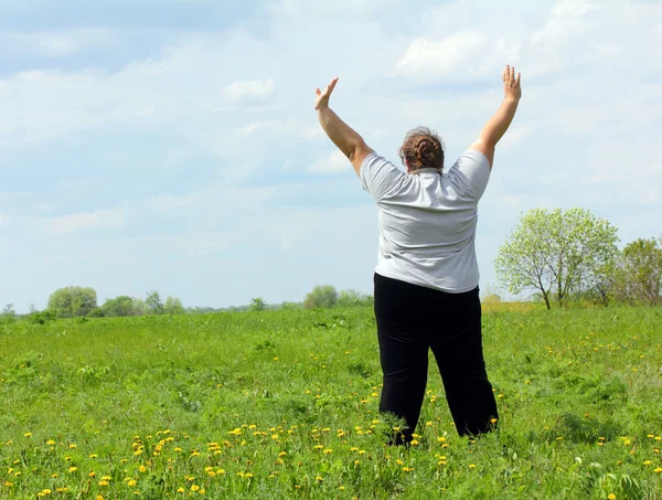 Femme en surpoids avec les mains vers le haut sur prairie — Photo