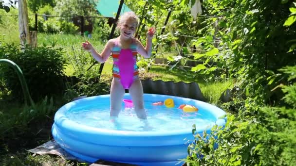 Девушка в надувном бассейне в летнем саду — стоковое видео