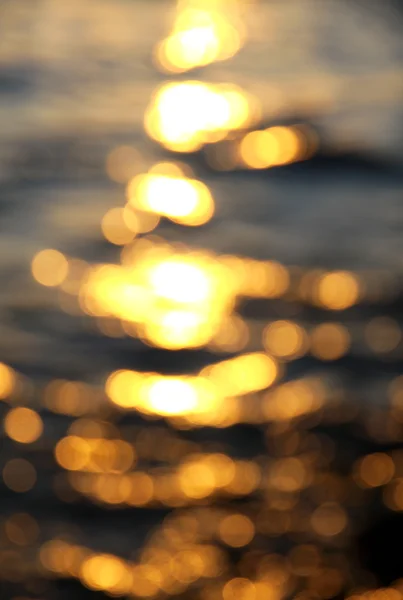 Fuera de foco fondo bokeh de agua de mar con reflejos de sol — Foto de Stock