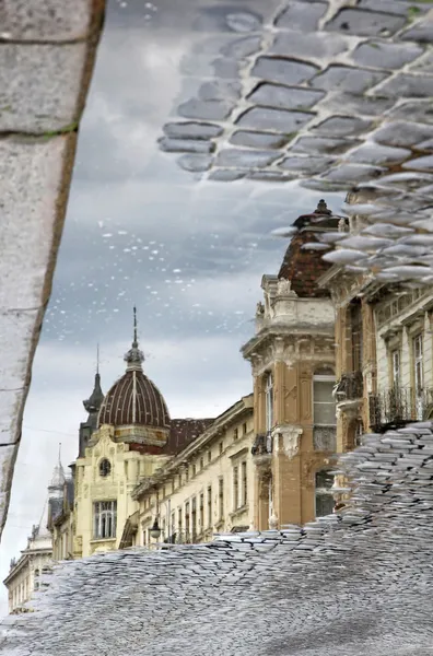 Buildings at the street reflecting in a puddle after rain — Stock Photo, Image