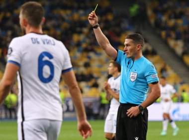KYIV, UKRAINE - SEPTEMBER 28, 2021: Hakem Istvan Kovacs (ROU), Kyiv 'deki NSC Olimpiyskyi stadyumunda oynanan UEFA Şampiyonlar Ligi maçında sarı kart gösteriyor