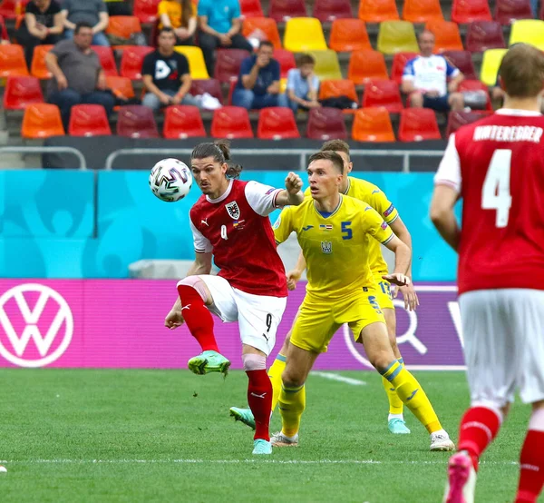 BÜKREŞ, ROMANIA - 21 Haziran 2021: Avusturyalı Marcel Sabitzer Ukraynalı Serhiy Sydorchuk ile UEFA EURO 2020 'deki Ulusal Arena Bucharest Stadyumu' nda oynanan maçta top için mücadele ediyor.