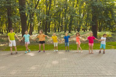 Yaz kampındaki çocuklar el ele tutuşuyorlar.