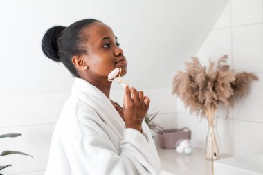 Gülümseyen genç kadın kameraya bakıyor cilt masajı yapıyor.