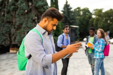 Öğrenci dışarıda durur ve bir yığın kitap tutar.