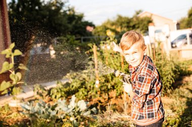 Çocuk bahçede su içerken gökkuşağının tadını çıkarıyor.